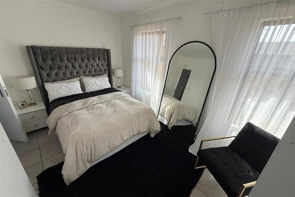 A well-lit bedroom featuring neutral walls and tiled flooring, providing a comfortable and functional living space.