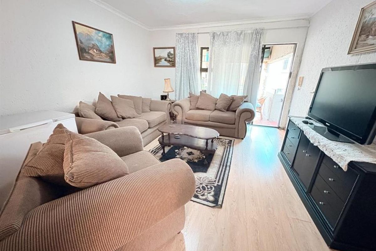 A living room featuring laminate flooring and a sliding glass door providing access to an outdoor area.