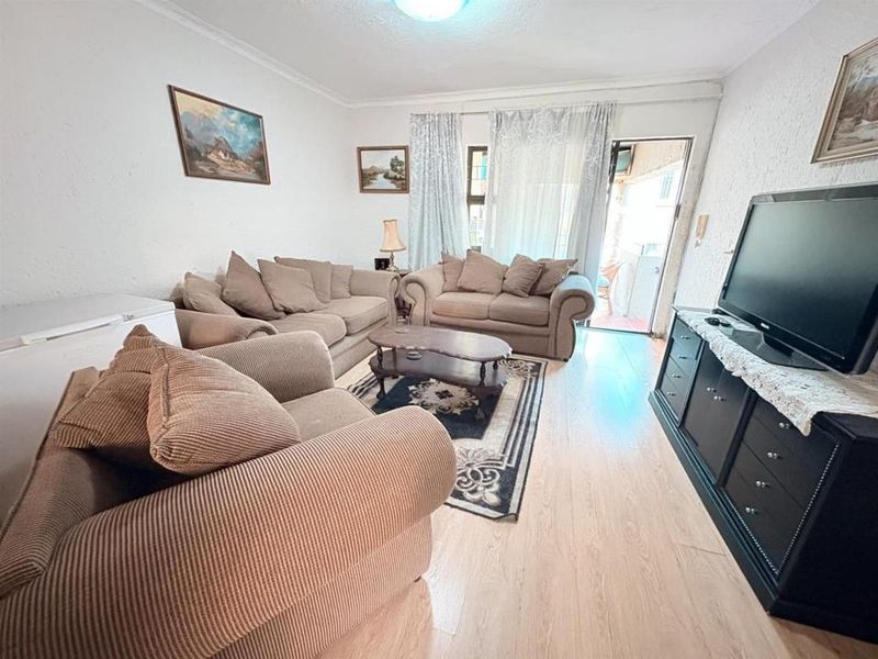 A living room featuring laminate flooring and a sliding glass door providing access to an outdoor area.