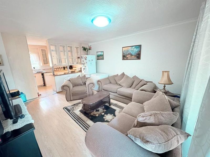 Open plan living area featuring laminate flooring and a connected kitchen with built-in cabinetry and countertops.
