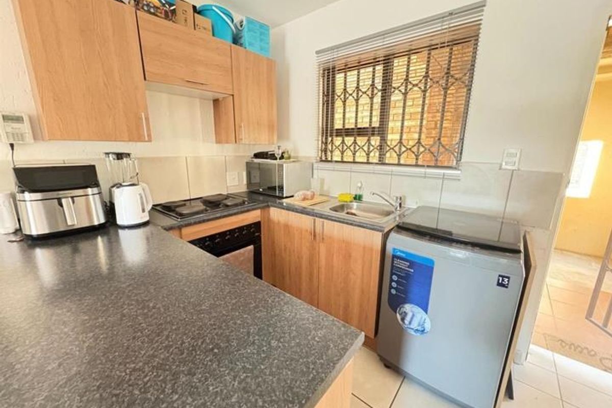 Compact kitchen featuring laminate cabinetry, dark countertops, built-in oven, hob, and tiled backsplash with a window overlooking the exterior.