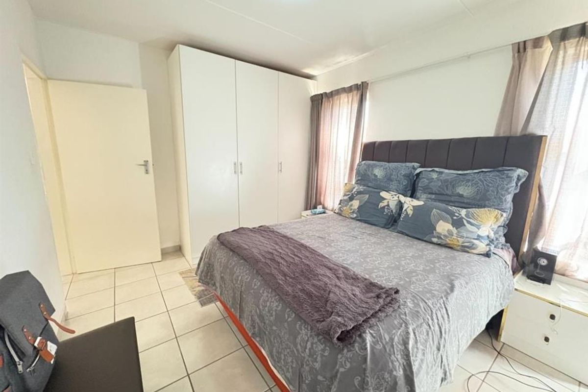 A functional bedroom featuring built-in cupboards and tiled flooring, providing a practical and neutral space for rest.