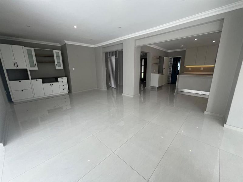 Spacious open-plan living and kitchen area featuring modern neutral finishes, large format floor tiles, and integrated cabinetry throughout.