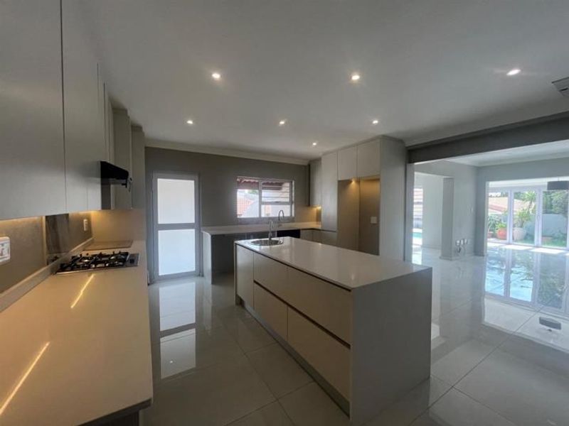 Modern, spacious kitchen featuring a large central island, stone countertops, gas hob, and sleek built-in cabinetry with recessed lighting.