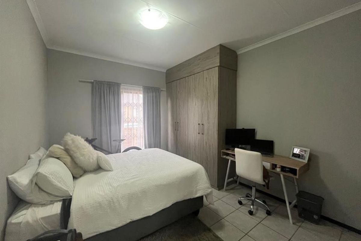 A functional bedroom featuring neutral wall tones, tiled flooring, and a built-in wardrobe providing ample storage space.