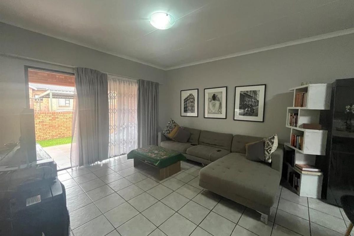 A comfortable living room featuring tiled flooring and a sliding glass door that provides direct access to the outdoor patio area.