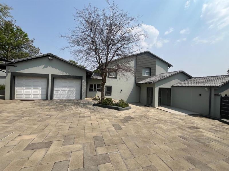 Front exterior view of a modern house featuring a double garage, extensive paved driveway, and a well-maintained facade with tiled roofing.