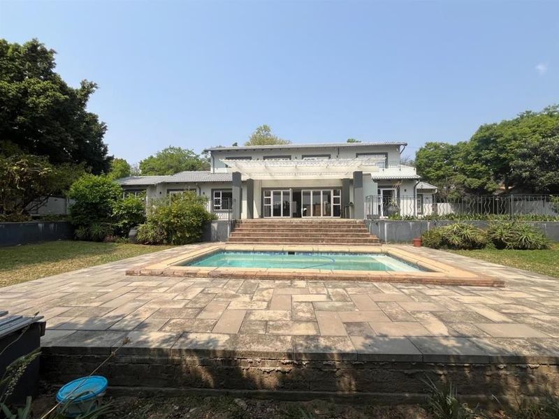 Rear view of the property featuring a swimming pool, paved patio area, pergola, and direct access to the main house via brick stairs.