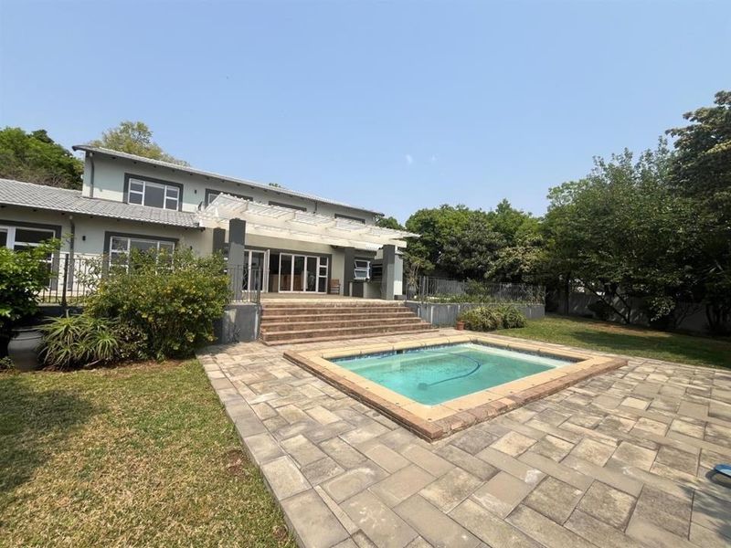 Rear view of the property featuring a paved patio area, a swimming pool, and a pergola structure leading to the main house.