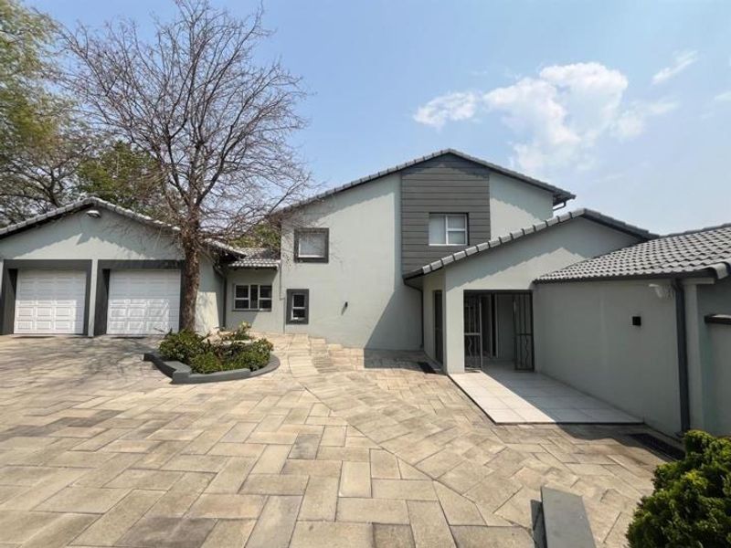 Front elevation of a modern house featuring a paved driveway, double garage, and a well-maintained exterior facade with neutral paint tones.