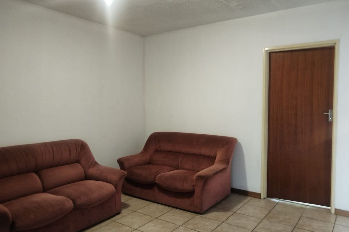 A simple living area featuring tiled flooring and a standard interior door, requiring cosmetic updates to improve the overall aesthetic.