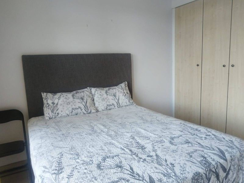 A bedroom featuring a built-in wardrobe with light wood-finish doors and neutral wall finishes.