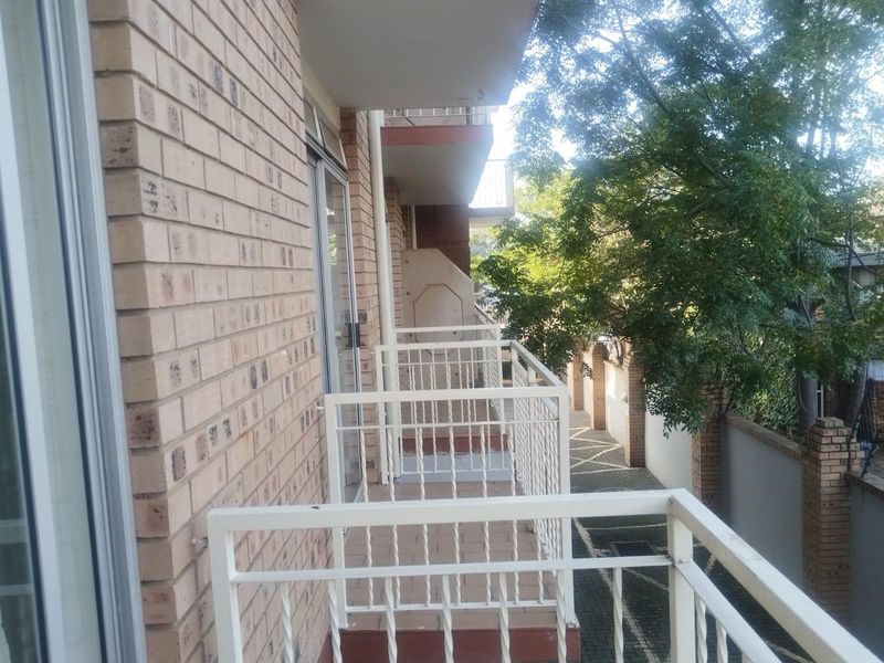 A functional apartment balcony featuring a metal balustrade, tiled flooring, and direct access to the living area via a sliding glass door.