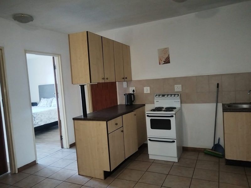 Functional kitchen featuring laminate cabinetry, tiled backsplash, and a freestanding stove, with direct access to the adjacent bedroom.
