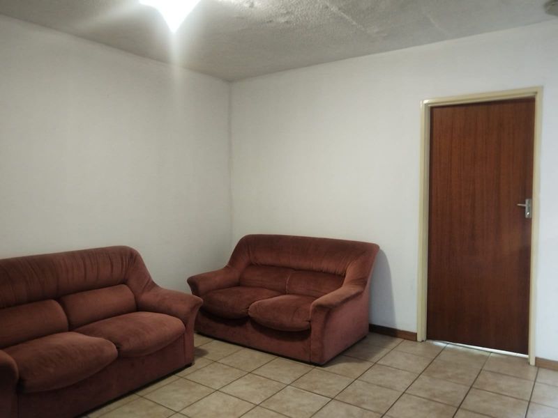 A simple living area featuring tiled flooring and a standard interior door, requiring cosmetic updates to improve the overall aesthetic.