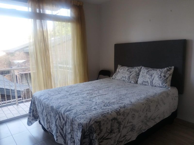 A bedroom featuring laminate flooring and a sliding glass door that opens onto a private balcony.