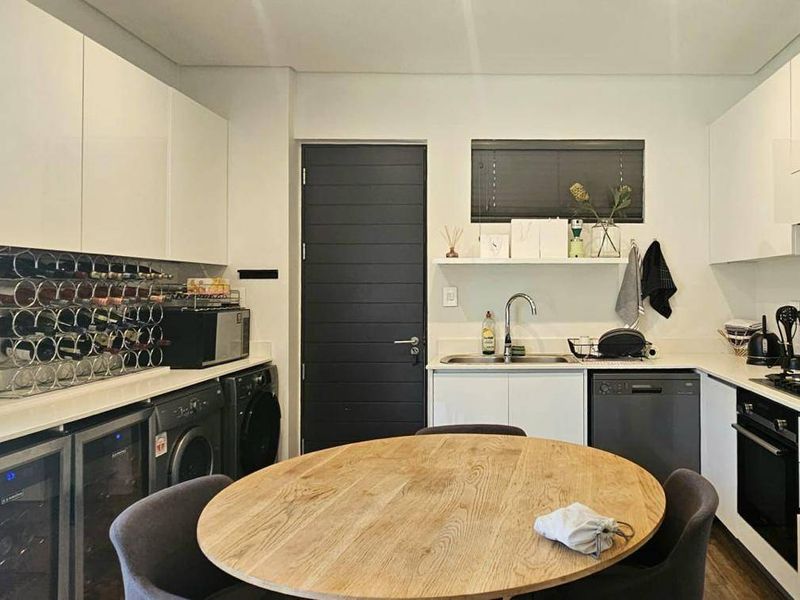 Modern kitchen featuring sleek white cabinetry, stone countertops, integrated appliances, and a gas hob, offering a clean and functional culinary space.