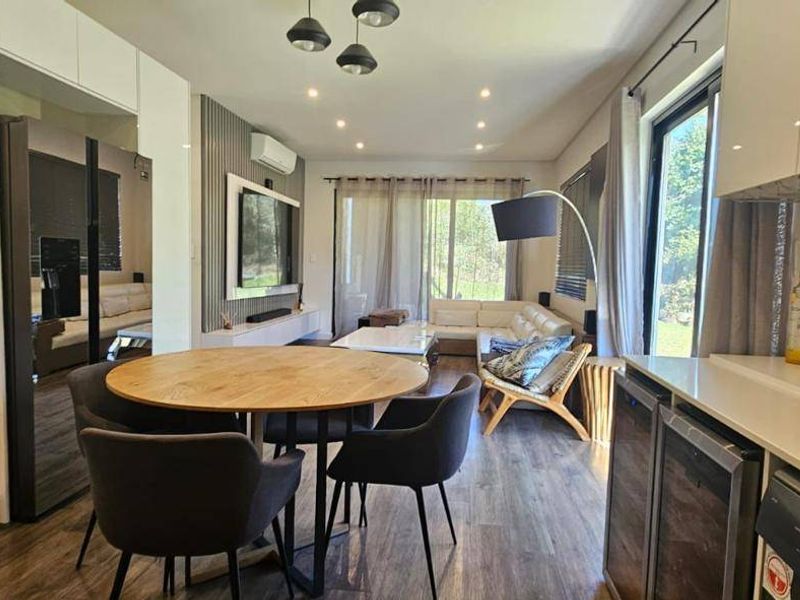 Modern open-plan living area featuring a sleek kitchen with integrated appliances, dining space, and seamless flow to the outdoor patio through sliding glass doors.