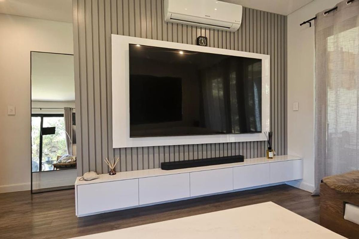Modern living room featuring a stylish slatted feature wall, built-in media cabinetry, and wall-mounted air conditioning unit.
