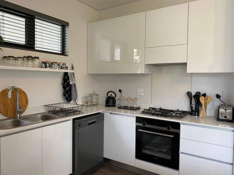 Modern kitchen featuring sleek white cabinetry, quartz countertops, gas hob, built-in oven, and integrated dishwasher in a clean, contemporary layout.