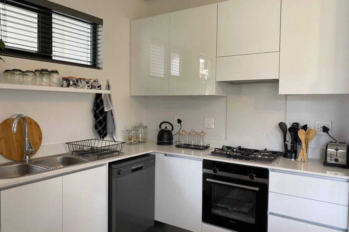 Modern kitchen featuring sleek white cabinetry, quartz countertops, gas hob, built-in oven, and integrated dishwasher in a clean, contemporary layout.