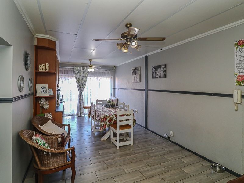 Open plan living and dining area featuring tiled flooring, ceiling fans, and built-in shelving, providing a functional space for daily living.