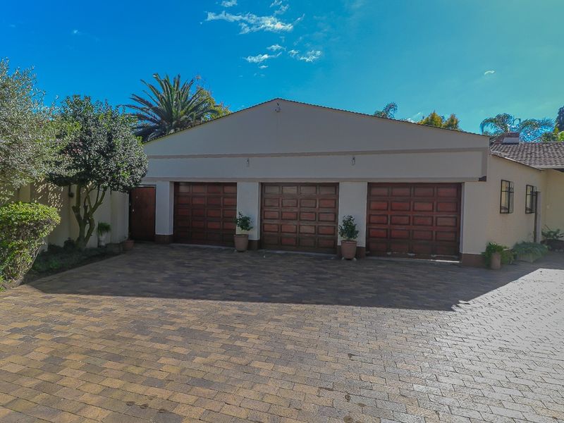 A well-maintained triple garage featuring wooden sectional doors and a spacious paved driveway area.