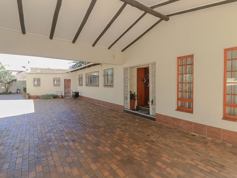 A spacious covered entrance area featuring brick paving, exposed timber beams, and secure access to the main residence.