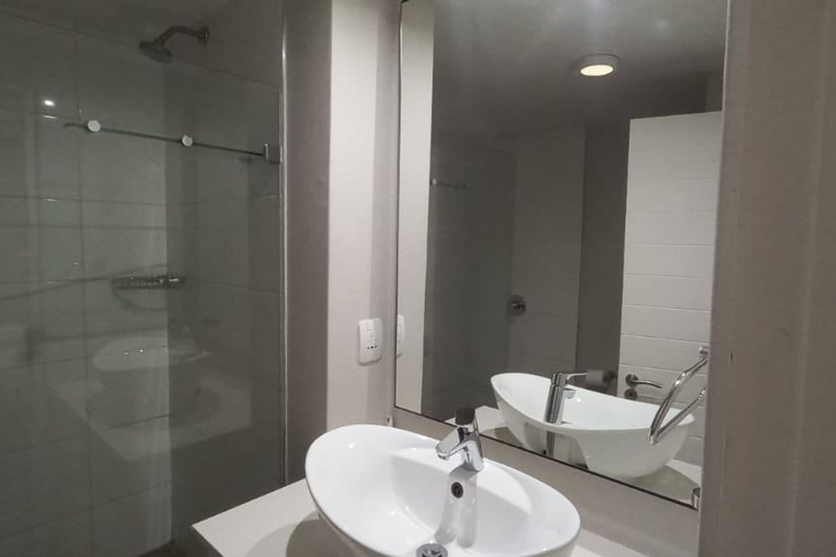 Modern bathroom featuring a vessel sink, large wall-mounted mirror, and a glass-enclosed walk-in shower with tiled walls.