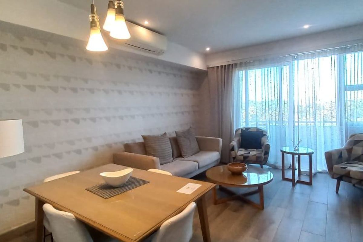 A well-maintained living and dining area featuring modern laminate flooring, recessed lighting, and a split-system air conditioner with access to a balcony.