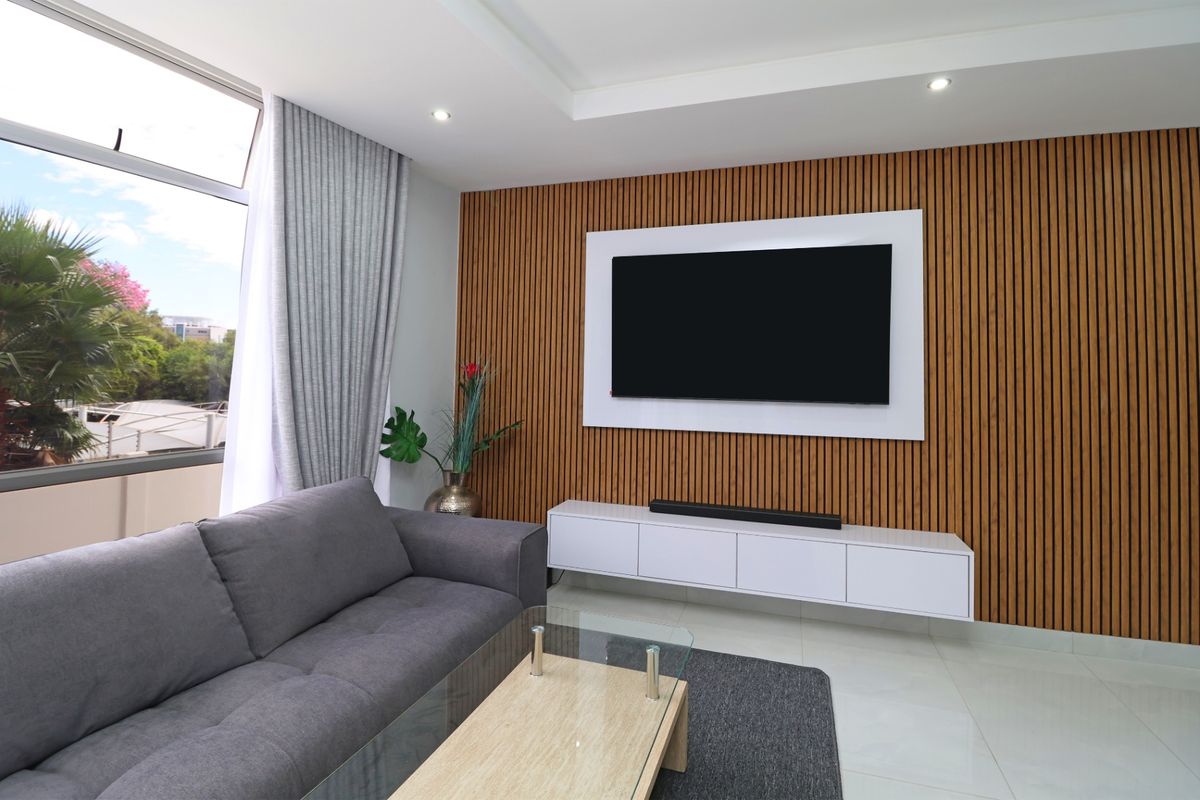 Modern living room featuring a decorative timber slat feature wall, built-in floating media console, and large windows providing ample natural light.