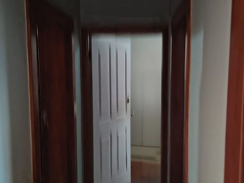 A narrow interior hallway featuring timber door frames and internal doors connecting to adjacent rooms.