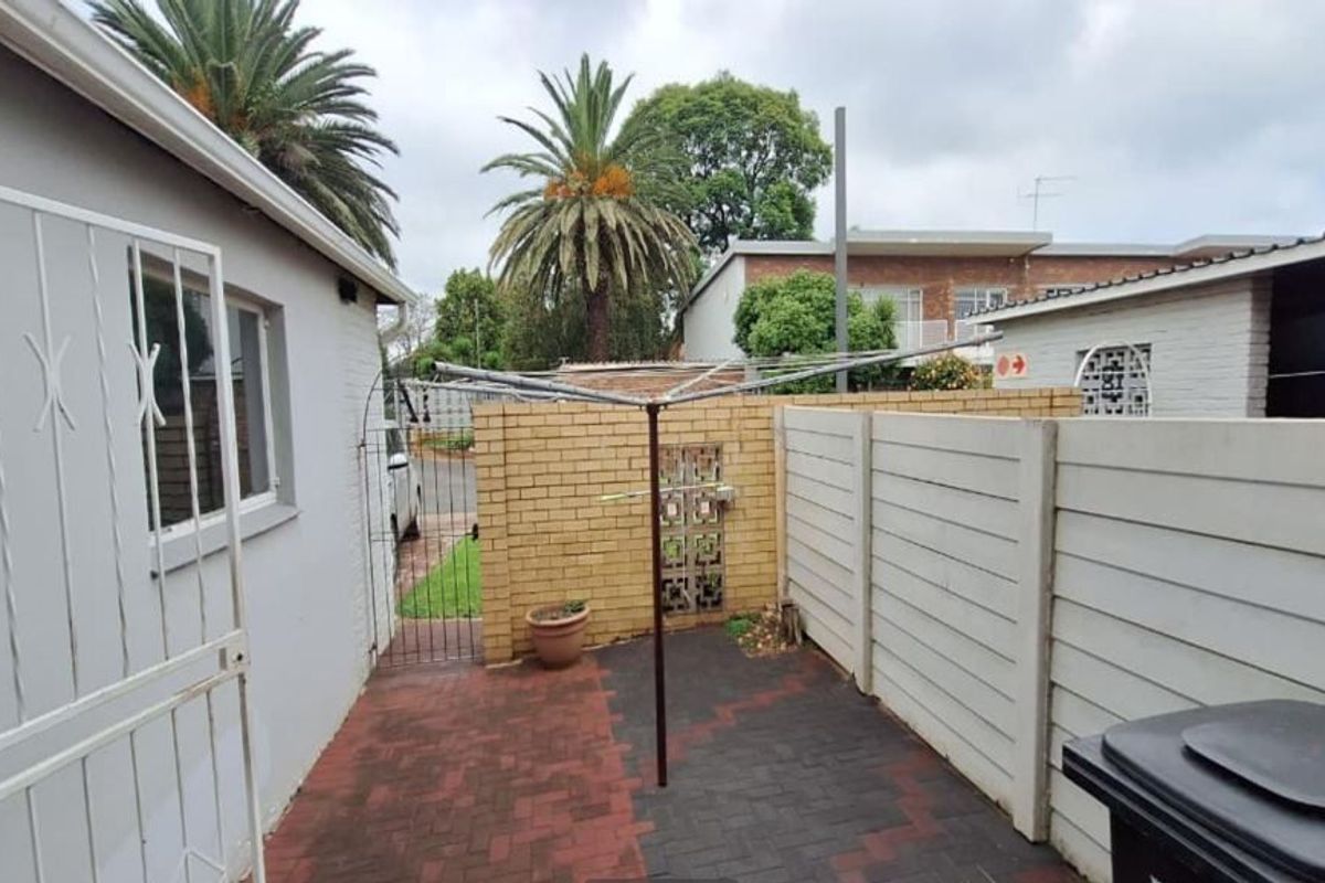 A paved rear courtyard area featuring a combination of face brick and precast concrete boundary walls with security access.