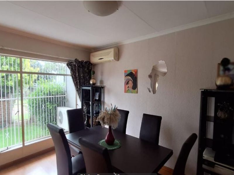 Dining room featuring a large window with security gate, wall-mounted air conditioning unit, and textured wall finish.