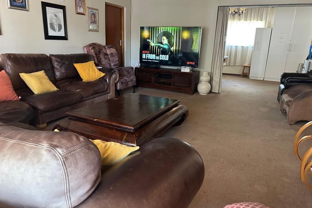 A spacious living room featuring carpeted flooring and a sliding room divider, providing access to an adjacent area.
