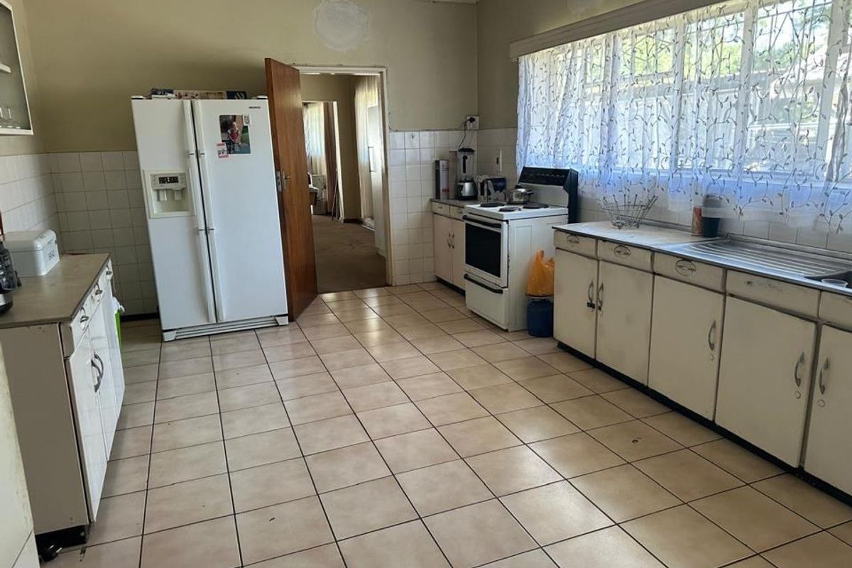 A functional kitchen featuring tiled flooring, built-in cabinetry, and a freestanding stove, offering a dated layout ready for modernization and renovation.