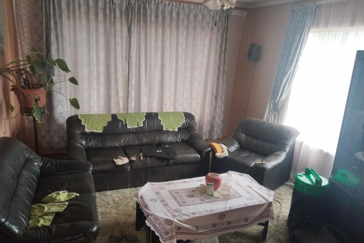 A dated living room featuring carpet flooring and a ceiling fan, offering a blank canvas for modernization and interior updates.