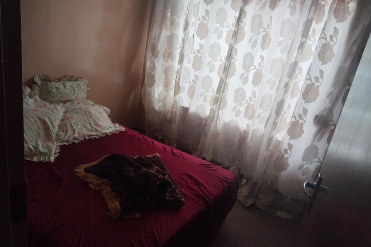 A compact bedroom featuring a window with curtains, providing a functional sleeping space.