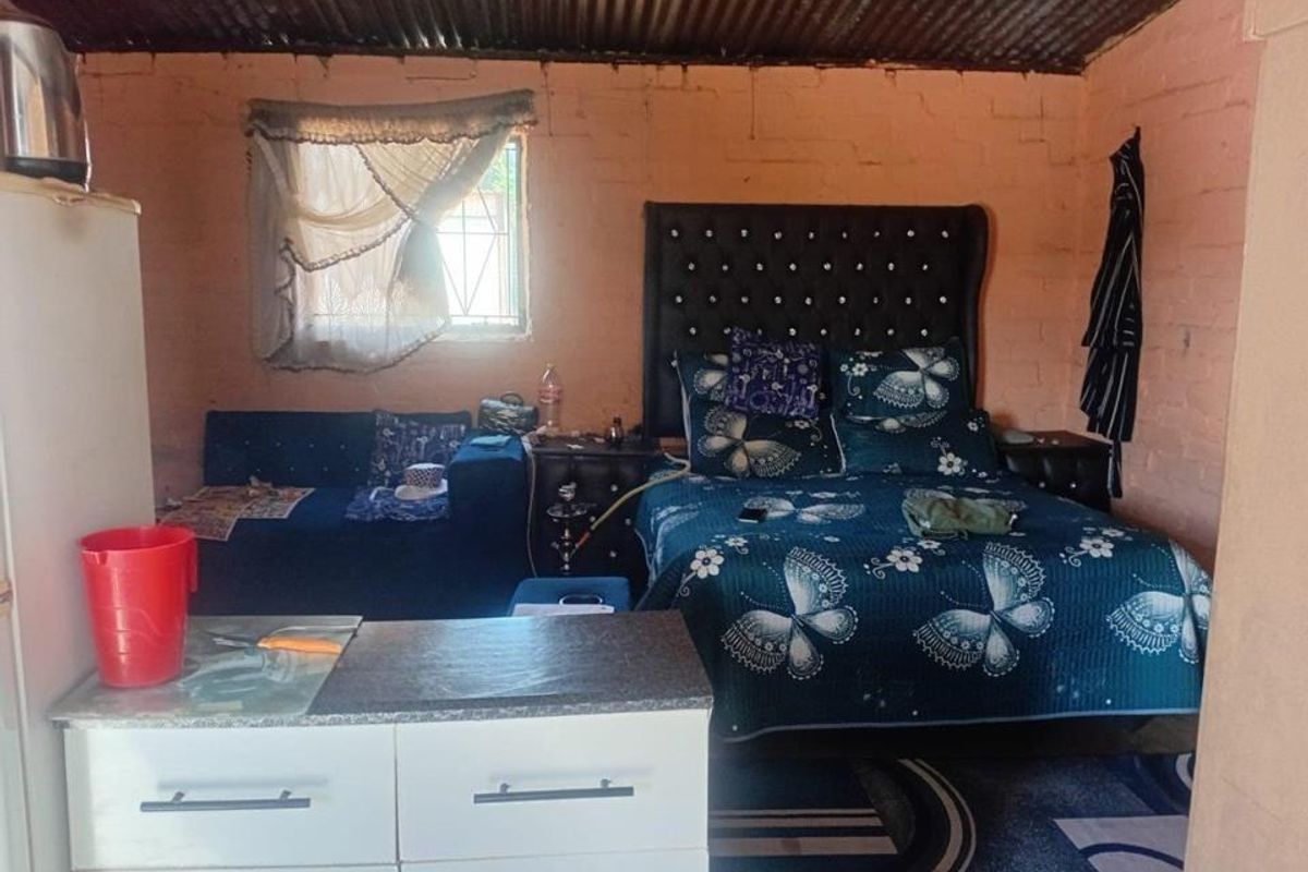A bedroom featuring exposed brick walls and a corrugated iron ceiling, providing a basic, unfinished aesthetic that could benefit from renovation and interior finishing.