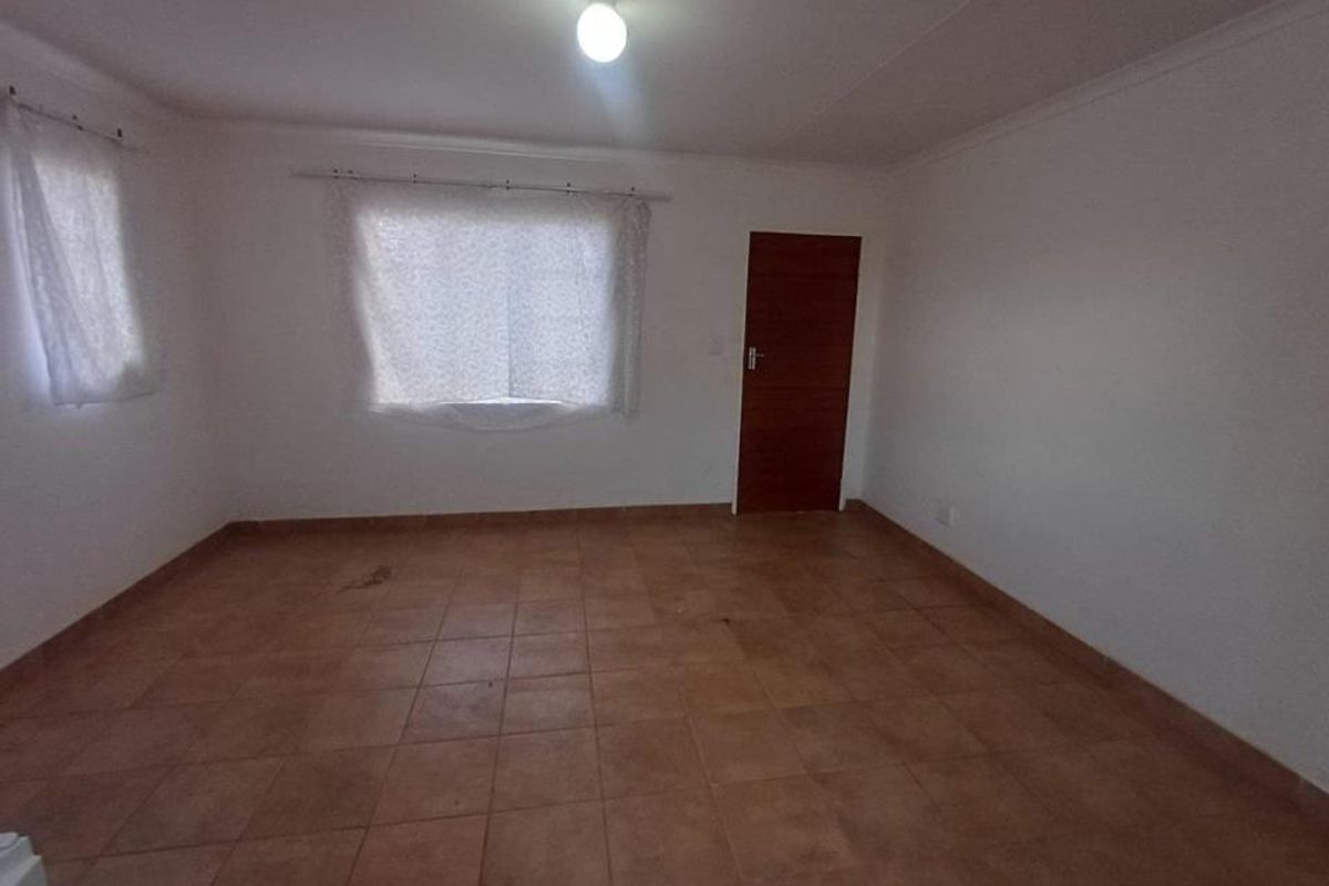 An empty bedroom featuring tiled flooring, a timber door, and cove cornicing, presenting a blank canvas for renovation or staging.
