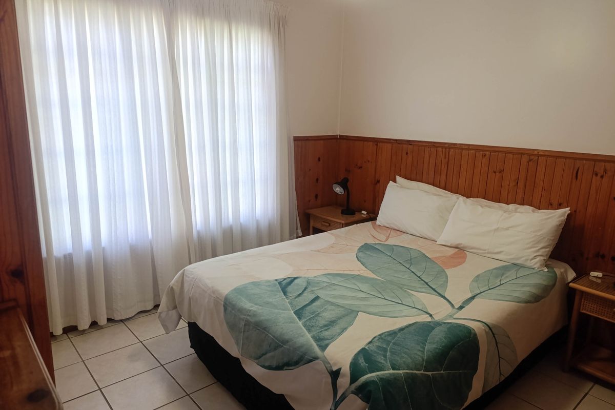 A bedroom featuring timber wall paneling and tiled flooring, offering a neutral base for potential interior updates.