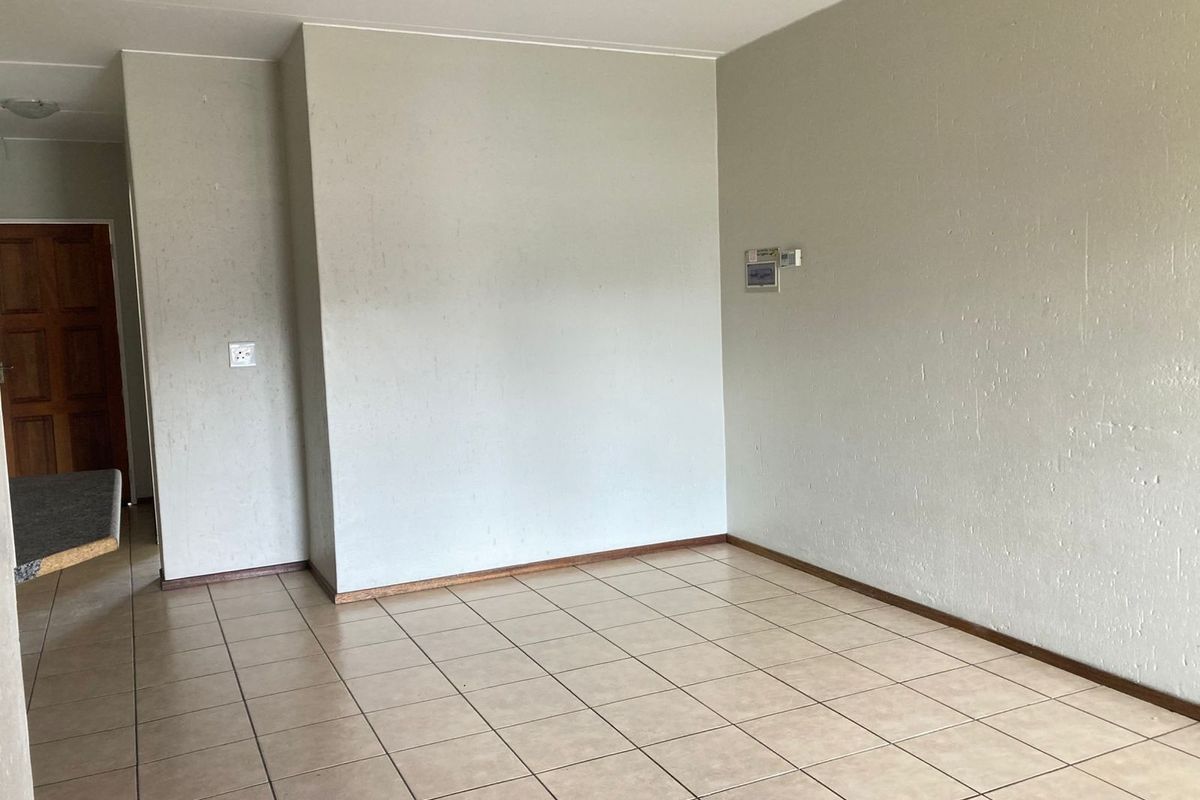 An empty living area featuring neutral tiled flooring and plain walls, providing a blank canvas for interior design and personalization.