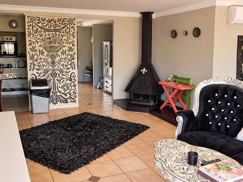 Open-plan living area featuring tiled floors, a built-in fireplace, and a wall-mounted air conditioning unit, with an adjacent kitchen space visible.