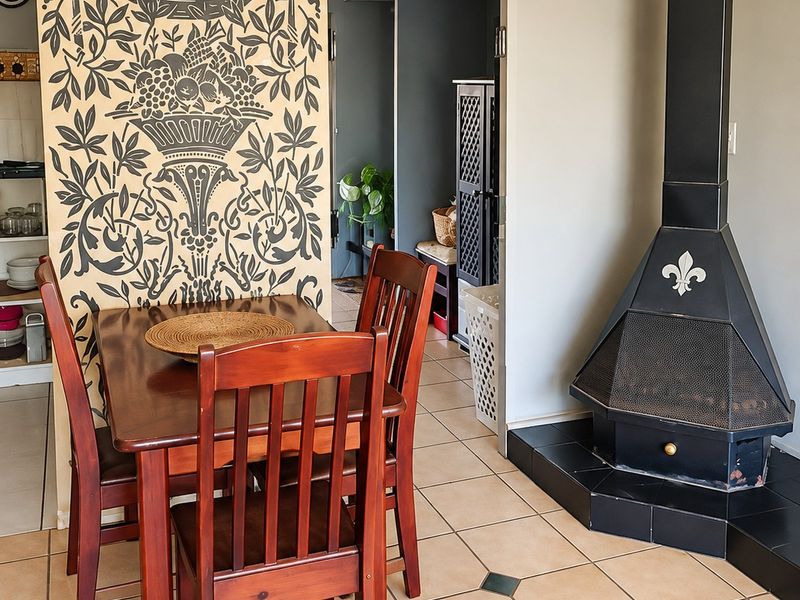 Dining area featuring tiled flooring and a prominent black freestanding fireplace, with an adjacent view into a secondary utility or kitchen space.