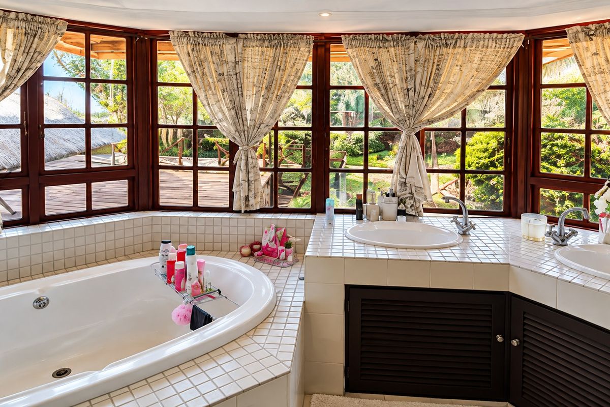 A bright bathroom featuring a built-in bathtub, dual vanity with tiled countertop, and large timber-framed windows overlooking a garden.