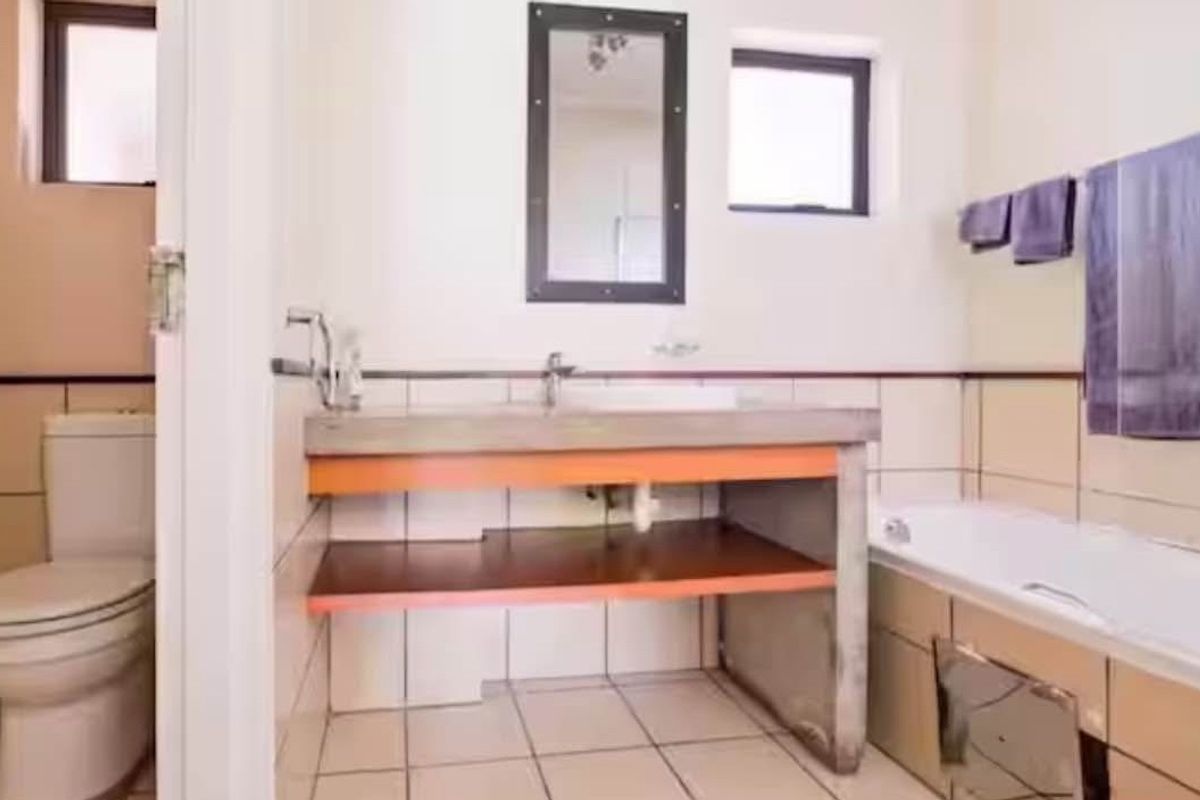 A functional bathroom featuring a built-in vanity, bathtub, and toilet with tiled finishes throughout.