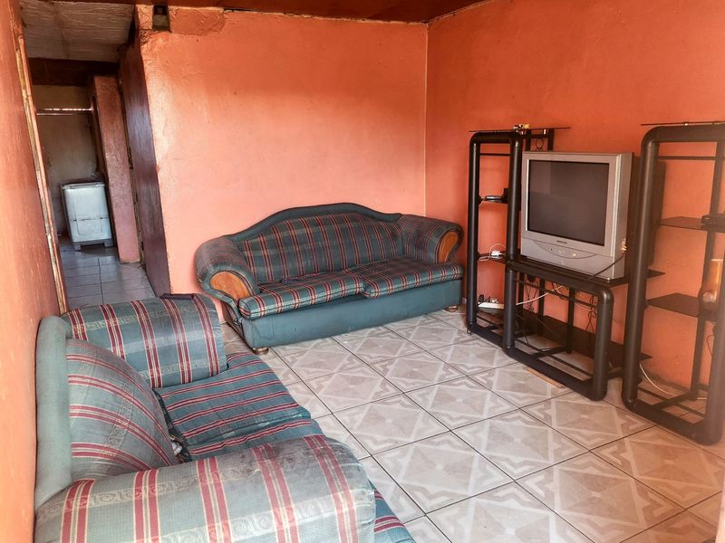 A living room area featuring tiled flooring and plastered walls, currently requiring maintenance and cosmetic updates to improve the overall condition.