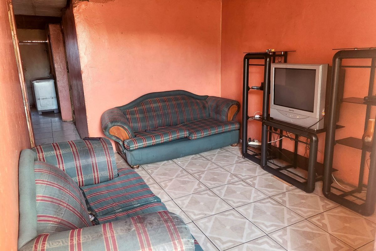 A living room area featuring tiled flooring and plastered walls, currently requiring maintenance and cosmetic updates to improve the overall condition.