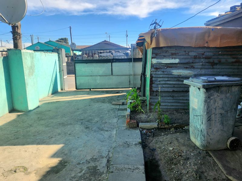 Front exterior area featuring a concrete driveway, metal sliding gate, and a corrugated metal structure.