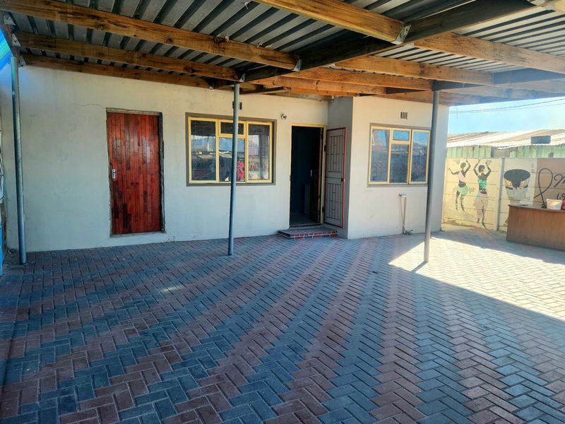 A spacious covered patio area featuring paved flooring, timber roof beams, and secure access points, ideal for outdoor entertaining or vehicle shelter.